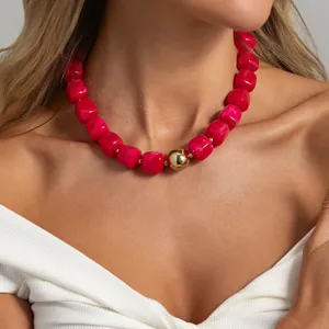 Primo piano di collana di perle di resina rosa con sfera dorata