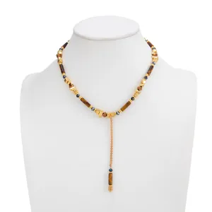 Detail van Y-vormige ketting met gouden kubuskralen en amberkleurige kralen op buste