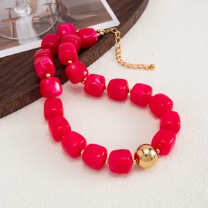 Dettaglio di collana in resina bohémien con perle magenta e una grande sfera dorata