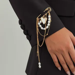 Elegant gold chain brooch with faux pearls and white heart pendant pinned on a black blazer