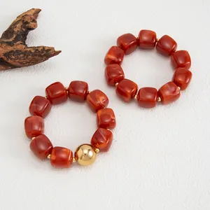 Dettaglio di braccialetti in resina stile Maillard con effetto marmo e sfera d'oro