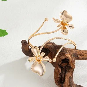 Vue détaillée de l'élégant bracelet de bras doré avec fleur à double couche sur bois