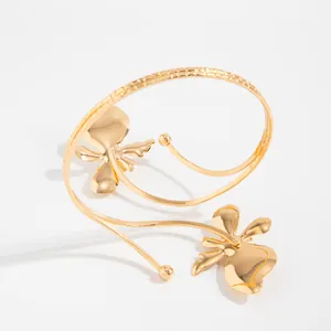 Gros plan d'un élégant bracelet de bras doré orné de deux fleurs en métal doré.
