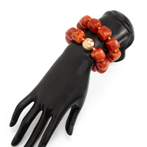 Primo piano di bracciali in resina marmorizzata con perla dorata su supporto nero.