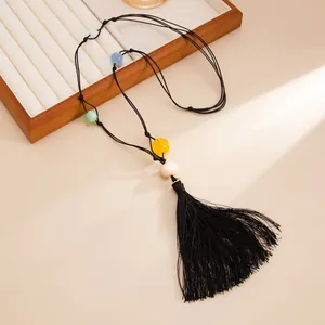 Close-up of hand-knotted black cord necklace with colorful resin beads and long black tassel detail.