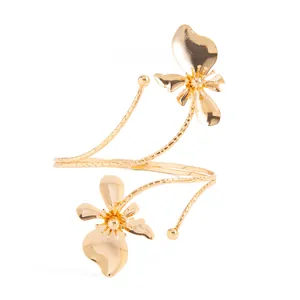 Détail d'un élégant bracelet de bras doré en spirale avec deux fleurs épanouies exquises