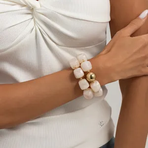 Primo piano di un bracciale in resina marmorizzata con una grande sfera dorata