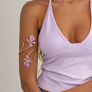Vue détaillée d'un bracelet de bras doré orné de deux fleurs en émail violet sur le bras.
