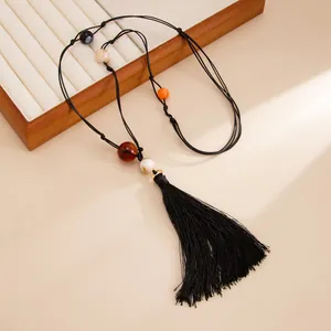 Detail of handmade knotted choker with colorful resin beads and long black silk tassel.