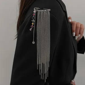 Detailed view of colorful zircon shoulder brooch with long silver tassel chains on black blazer