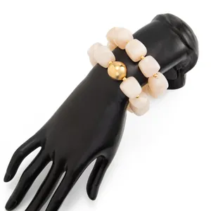 Dettaglio di bracciale elastico in resina marmorizzata crema su espositore a mano nera