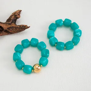 Dettaglio di perle in resina turchese e una sfera dorata su bracciali retrò.
