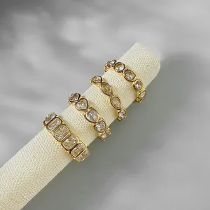 Close-up of four gold-plated stainless steel rings with clear zirconia settings.