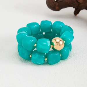 Primo piano di un bracciale elastico in resina marmorizzata verde con perla d'oro