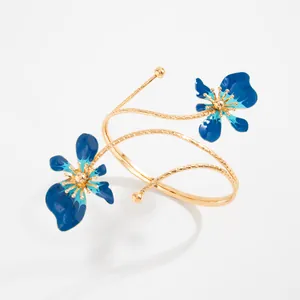 Détail du bracelet de bras doré avec fleurs en émail bleu et design en spirale