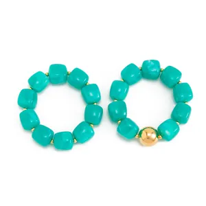Dettaglio di bracciali elastici in resina marmorizzata color teal con perla dorata