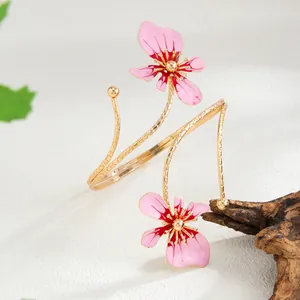 Vue détaillée du bracelet de bras élégant en émail rose avec design enveloppant doré.