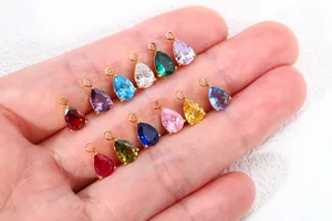 Detalle de varios colgantes de circonita de colores con forma de pera en una mano.