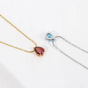 Primer plano de collares de oro y plata con colgantes de circón rojo y azul de pera