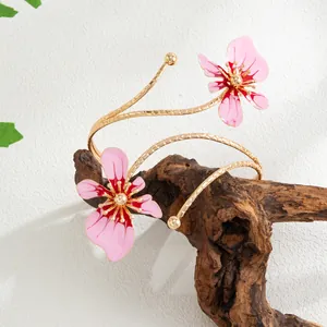 Gros plan d'un élégant bracelet de bras doré à deux couches avec des fleurs en émail rose.