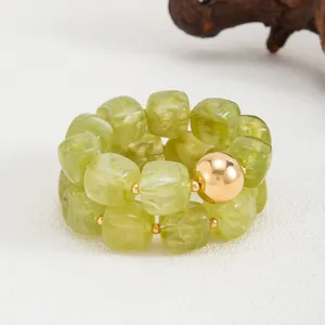 Primo piano di un braccialetto in resina verde marmorizzata con sfera in metallo oro.