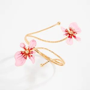 Gros plan d'un élégant bracelet de bras doré en spirale avec des fleurs en émail rose