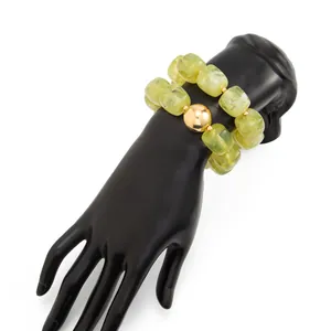 Dettaglio macro professionale di bracciale in resina verde marmo con grande perla dorata