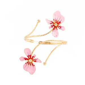 Vue détaillée d'un bracelet de bras spirale doré avec deux fleurs en émail rose.