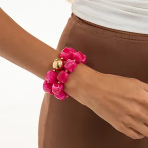 Primo piano di un bracciale in resina marmorizzata fucsia con perla oro