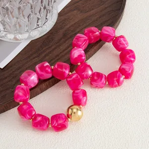 Vista dettagliata di bracciali in perline di resina rosa con accenti dorati su legno
