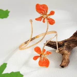 Gros plan d'un brassard élégant avec fleurs en émail orange et design en spirale dorée