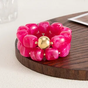 Vista dettagliata di perle in resina marmorizzata fucsia su bracciale elastico retro.