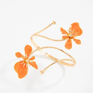 Vue détaillée d'un bracelet de bras spirale doré orné de fleurs en émail orange.