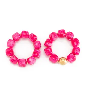 Vista dettagliata di perle in resina marmorizzata rosa con accenti dorati su bracciali