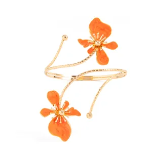 Vue détaillée d'un bracelet de bras à fleurs orange avec un design en spirale dorée.