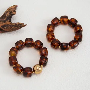 Macro di braccialetti in resina ambrata stile Maillard con una grande perla dorata