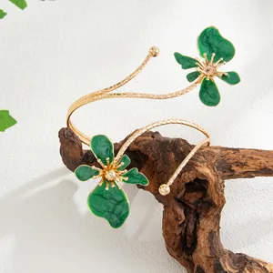 Détail du bracelet de bras fleur en émail vert avec design doré sur bois.