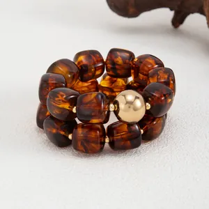 Primo piano di un bracciale in resina stile Maillard con perle ambrate e dettaglio oro