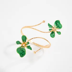 Vue macro détaillée d'un élégant bracelet de bras doré avec des fleurs en émail vert