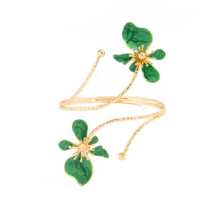 Vue détaillée d'un bracelet de bras doré avec des fleurs en émail vert et des motifs.