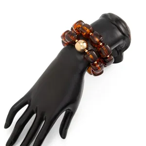 Vista dettagliata del bracciale in resina ambrata stile Maillard su supporto a mano nero