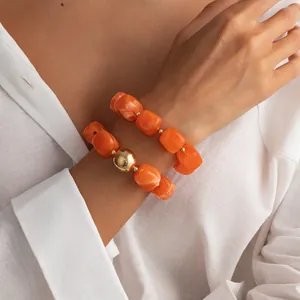 Primo piano di braccialetti elastici in resina marmorizzata arancione su un polso.