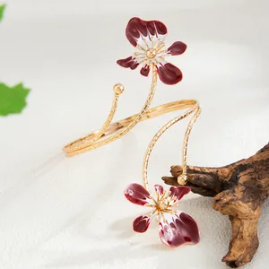Détail exquis d'un bracelet de bras doré à double couche avec des fleurs en émail rouge