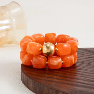 Dettaglio del bracciale in resina marmorizzata arancione stile Maillard con perla d'oro