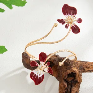 Vue détaillée d'un bracelet de bras torsadé doré avec fleurs en émail bordeaux