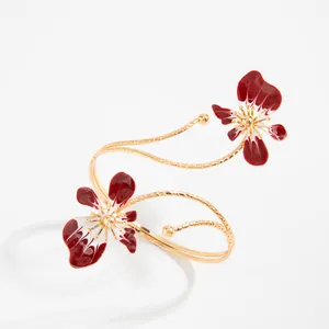 Bracelet de bras spirale doré élégant avec des fleurs en émail rouge détaillées.