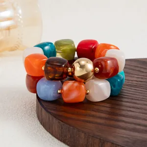 Dettaglio ravvicinato di braccialetti in resina marmorizzata su un supporto di legno.
