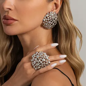 Close-up of oversized silver honeycomb earrings and matching ring on female model