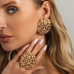 Close-up detail of gold honeycomb textured earring and matching ring set on a model.