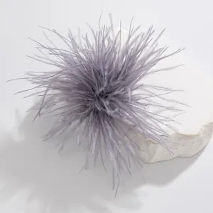 Macro detail of a soft grey-purple ostrich feather brooch on a white stone base